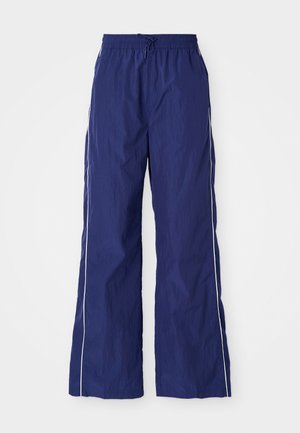 Navyblauwe, lichte, wijde broek met een elastische tailleband en trekkoord, met witte zijstrepen en een geplooide textuur.
