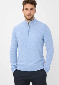 Hellblauer Strickpullover mit Reißverschlusskragen, gerippten Bündchen und Saum. Die Textur ist weich und leicht meliert für zusätzliche Tiefe.