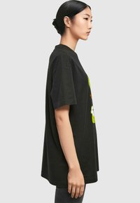 Black cotton t-shirt with short sleeves, loose fit, featuring colorful graphic print. Soft texture, round neckline, hip-length design.