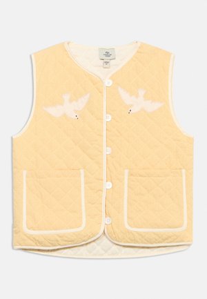 Prešívaná svetložltá vesta bez rukávov s bielymi gombíkmi, dvoma prednými vreckami a bielou výšivkou vtáka na každej strane hrudníka.