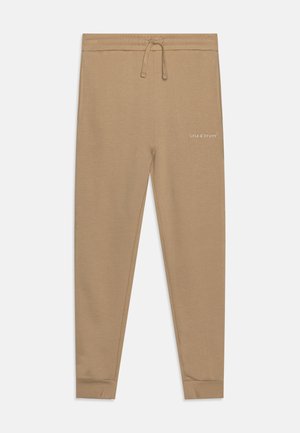 Pantalons de survêtement beiges avec un cordon de serrage à la taille, des poignets côtelés et un petit logo blanc sur la cuisse. Fabriqués en tissu doux et texturé.