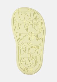 Keltainen kumipohja, jossa on kohokuvioituja eläin- ja abstrakteja kuvioita. Sisältää "Camper"-brändäyksen ja sileän pinnan. Pyöreä muoto.