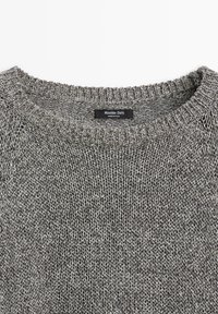 Grå strikket sweater med ribbet rund halsudskæring og et sort mærke med teksten "Massimo Dutti Made in Italy" ved kraven.