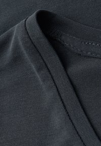Dunkelgrauer Stoff, weiche und glatte Textur, mit einem gebogenen Ausschnitt und sauberen Nähten, zeigt ein einfaches Design ohne Muster.