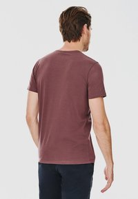 Ciemnofioletowa koszulka z krótkim rękawem, wykonana z mieszanki bawełny, w fasonie z okrągłym dekoltem, gładka tekstura, widok z tyłu ukazuje prosty styl bez ozdób.