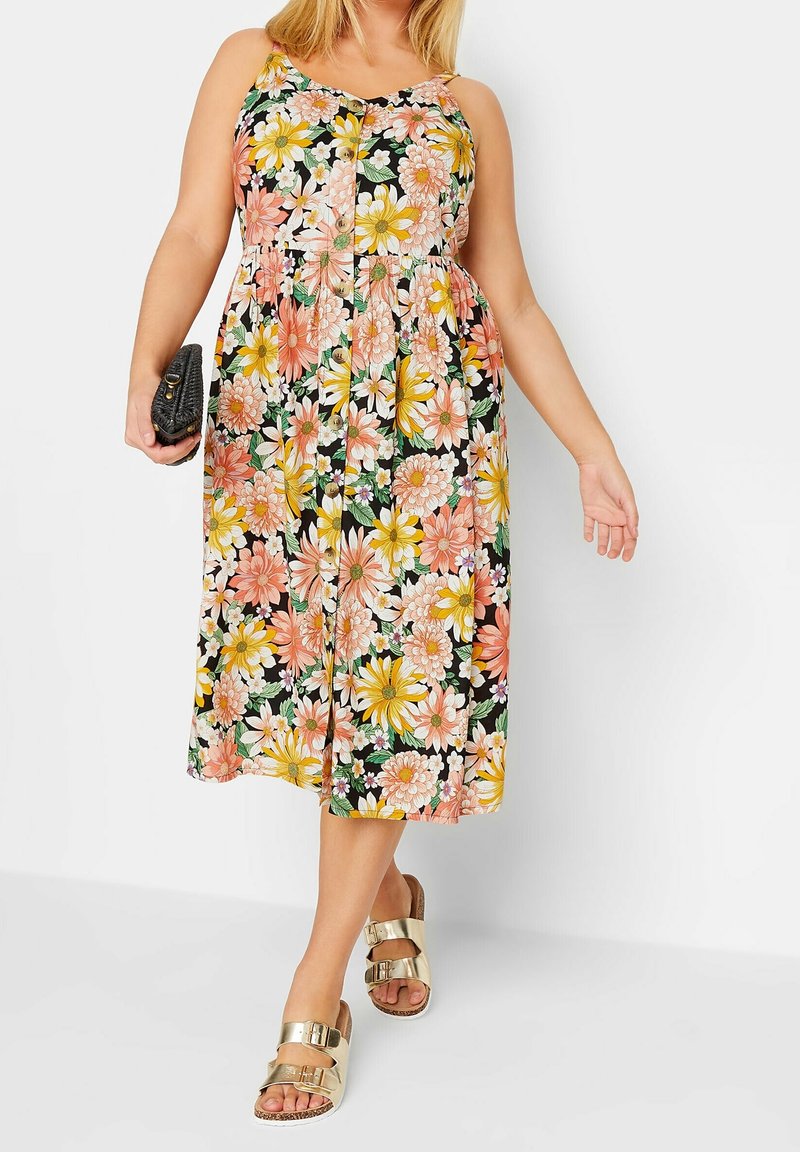 Květinové maxi šaty se špagetovými ramínky, s černým pozadím, velkými růžovými, žlutými a bílými květinami, a designem s nařaseným pasem.