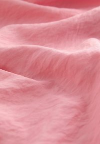 Tessuto rosa con una consistenza morbida e liscia, caratterizzato da pieghe sottili e un aspetto leggero, ideale per diverse applicazioni tessili.