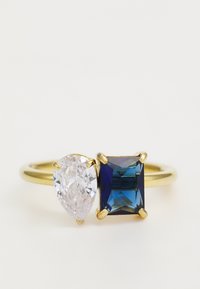 Anello in oro con un gemma chiara a forma di pera e un gemma blu rettangolare, entrambi incastonati in quattro griffe, con una fascia liscia.