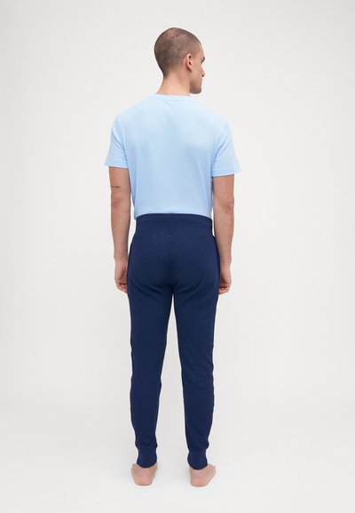 Ensemble de pyjama comprenant un haut bleu clair à manches courtes avec une finition texturée et un pantalon bleu marine foncé à coupe fuselée et taille élastique.