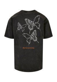 Sort bomulds T-shirt med en ryggrafik af tre hvide sommerfugledesign og teksten "Hvor frygt møder frihed" i orange.