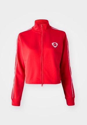 Giacca rossa con zip e colletto alto, strisce bianche ai lati e un logo a forma di cuore sul lato sinistro del petto. Realizzata in un tessuto liscio e elasticizzato.