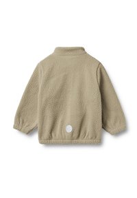 Veste en polaire beige clair avec une texture. Elle possède un col montant et un patch logo circulaire à l'arrière.