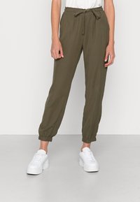 Pantalon de jogging ample vert olive avec une taille élastique et un détail noué, doté de poignets élastiques aux chevilles.