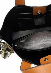 Czarna skórzana torebka na ramię z brązowym uchwytem, wyposażona w kieszeń wewnętrzną na zamek błyskawiczny oraz ozdobny szalik w desenie.