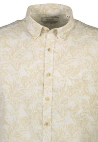 Camicia button-up in crema chiaro con un discreto motivo di foglie gialle. Presenta un colletto classico, tasca frontale e bottoni beige. Design a vestibilità regolare.