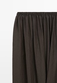 Donkerbruine geplooide rok met een elastische tailleband en een licht gekreukte stoftextuur.