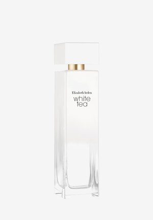 Korkea suorakaiteen muotoinen kirkas lasipullo, jossa valkoinen läpikuultamaton neste, kullanvärinen kaula ja suuri valkoinen neliönmuotoinen korkki, jossa teksti "Elizabeth Arden white tea".