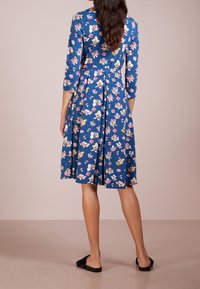 Blå blommig klänning med trekvartslånga ärmar, plisserad kjol, i ett mjukt tyg, med flerfärgade blommönster och en figursydd midja.