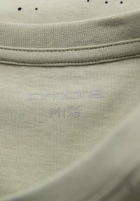 Lichtgroene katoenen T-shirt kraag met zichtbare stiksels, voorzien van "ombre" merk en maatlabel "M" met Europese maat "48."