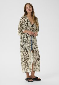 Kimono léger et transparent en crème avec un motif de rayures de tigre marron. Présente des manches amples, un décolleté en V et un long devant ouvert.