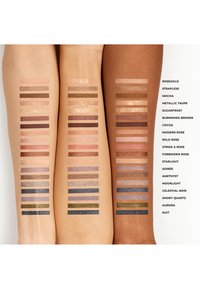 Fargeprøver av forskjellige øyenskygger på to armer, som viser metalliske og matte overflater i gull, bronse, rosa, lilla og grønne toner.