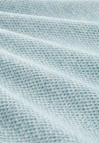 Hellblaues gestricktes Gewebe mit einem strukturierten, gewebten Muster. Das Material zeigt eine weiche, glatte Oberfläche mit subtilen Farbabstufungen.