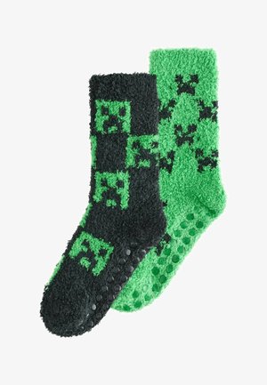 Șosete pufoase în negru și verde. O șosetă are un model pixelat; cealaltă are puncte texturate antiderapante pe talpă. Material moale și confortabil.