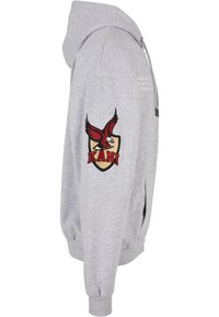 Hoodie gris avec une fermeture éclair sur le devant, des poches latérales et des poignets côtelés. Présente un écusson brodé d’aigle rouge et noir portant la mention "KANI."