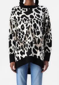 Knit svetr v černé, bílé a béžové leopardí potisky s ribovanými černými detaily. Má volný střih a kleslé ramena.
