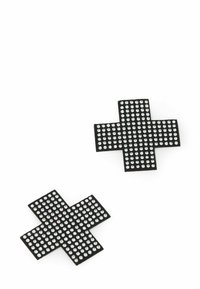 Dvě černé nášivky ve tvaru kříže zdobené rovnoměrně rozmístěnými malými stříbrnými cvočky na bílém pozadí.