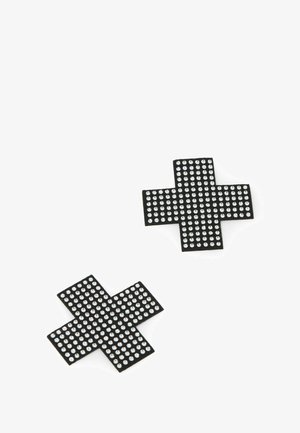 Due toppe nere a forma di croce decorate con piccoli borchie d'argento uniformemente distribuite su uno sfondo bianco.