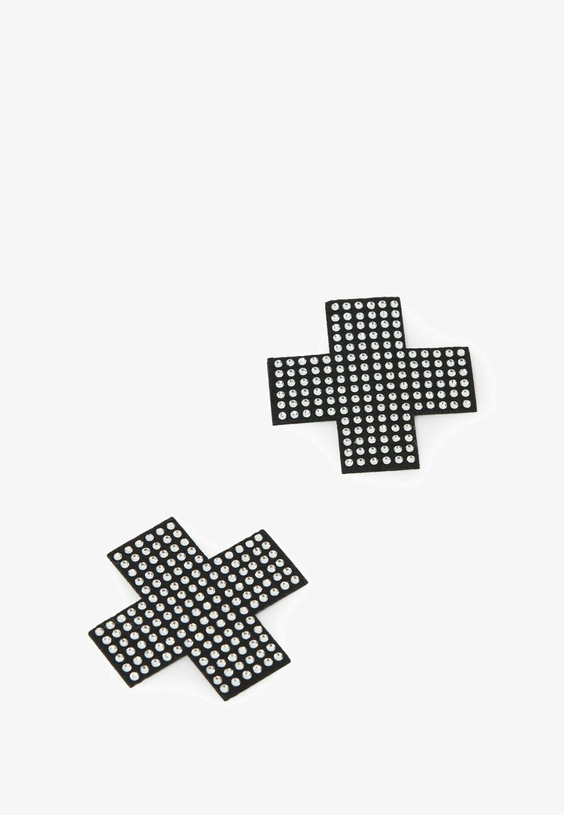 Dvě černé nášivky ve tvaru kříže zdobené rovnoměrně rozmístěnými malými stříbrnými cvočky na bílém pozadí.