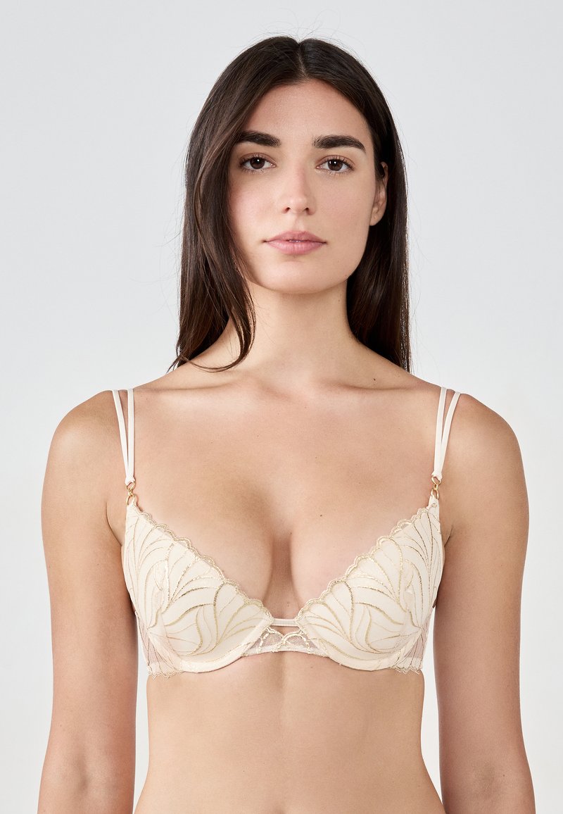 Lace-trimmed triangle bra in nude with delicate leaf-pattern embroidery, featuring adjustable straps and gold hardware accents.