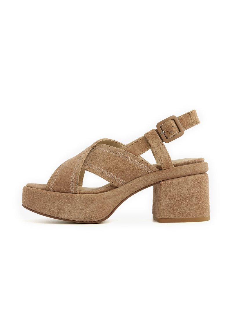 Beige suede platform sandals with cross-strap design, adjustable ankle buckle, and chunky heel. Subtle stitching detail enhances texture.