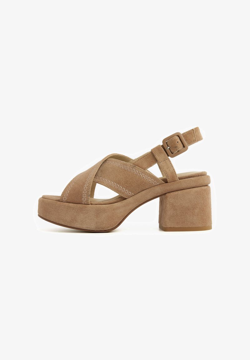 Beige suede platform sandals with cross-strap design, adjustable ankle buckle, and chunky heel. Subtle stitching detail enhances texture.