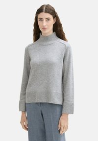 Pulover gri dintr-un material tricotat moale, având guler înalt, mâneci lungi, manșete ribbate și un croi lejer. Simplitate, fără modele vizibile.