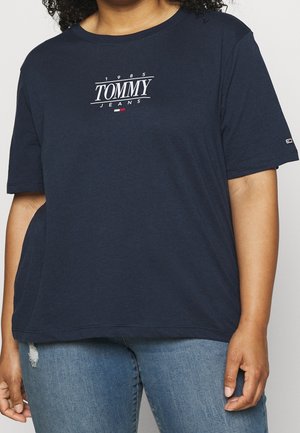 T-shirt en coton bleu marine à manches courtes, col rond, avec le logo blanc "TOMMY JEANS". Coupe légèrement ample avec coutures latérales visibles.