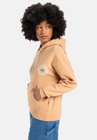 Pfirsichfarbene Kapuzenjacke mit einer Fronttasche, weißem Logo-Druck und Kordelzug. Weicher Stoff mit gerippten Bündchen und Saum.