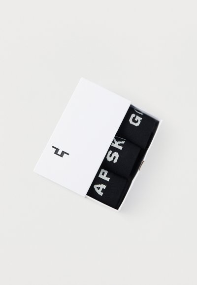 Calzini di cotone neri con testo bianco confezionati in una scatola rettangolare bianca con un logo minimalista sulla parte anteriore.