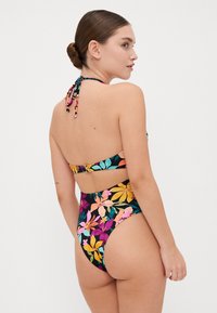 Hoog-waardig bikini-set met een bloemmotief in levendige kleuren op een zwarte achtergrond, met een gestrikte halternek en een haaksluiting op de rug.
