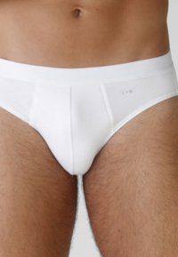 Slip di cotone bianco con una texture liscia, dotato di una cintura elastica a contrasto. Dettaglio del logo discreto sul davanti.
