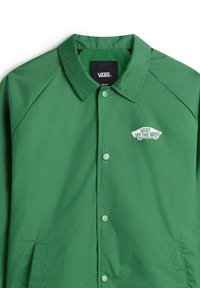 Groene windjack met een kraag, drukknoopjes en zijzakken. Bevat een wit 'VANS' logo met de tekst 'OFF THE WALL'. Soepele textuur.