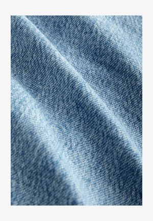 Modrý denimový materiál s texturovanou tkaninou a viditelnými diagonálními vzory, příjemný na dotek, s hladkým povrchem a jemnými barevnými variacemi.