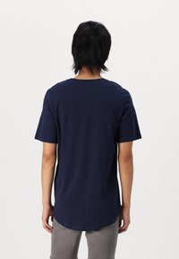 Marineblaue T-Shirt mit kurzen Ärmeln und abgerundetem Saum. Aus weicher Baumwolle gefertigt, mit einem einfachen, einfarbigen Design ohne Verzierungen.