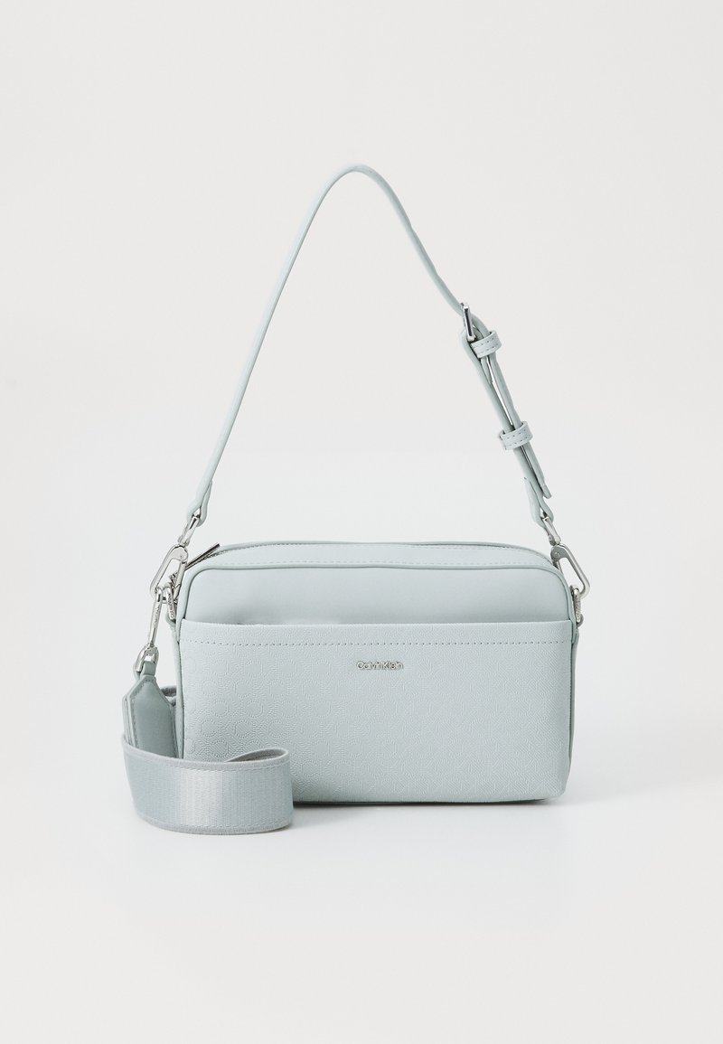 Borsa a tracolla di colore azzurro chiaro realizzata in materiale sintetico testurizzato. Caratterizzata da una chiusura con zip, una tracolla regolabile e un logo discreto sul davanti.