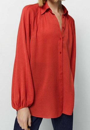 Rode blouse met lange mouwen, knoopsluiting aan de voorkant, losse pasvorm en elastische boorden, gedragen met donkerblauwe broek.