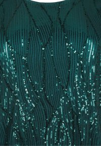 Teal paljettyg med vågiga mönster och varierade texturer. Reflekterande paljetter skapar visuell intresse mot en jämn bakgrund.