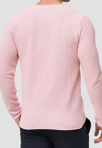Rosa Langarmpullover mit strukturiertem Strick. Besitzt einen runden Ausschnitt und einen leicht geschwungenen Saum. Die Rückansicht zeigt schmal geschnittene Ärmel und ein dezentes Muster.