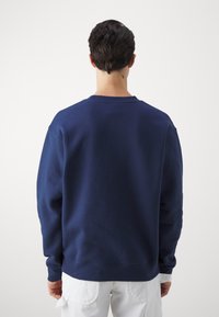 Mörkblå crewneck sweatshirt i mjukt bomullsblandning, med långa ärmar och en bekväm passform. Klassisk design med ribbade muddar.