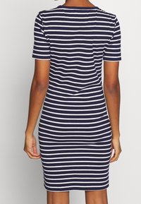 Sukienka w niebiesko-białe paski z krótkimi rękawami, dopasowanym fasonem, okrągłym dekoltem i subtelnym detalem szwu na plecach. Gładki materiał z mieszanki bawełny.